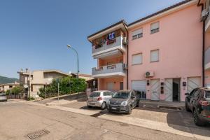 two cars parked in front of a pink building at L'acquario in Villasimius