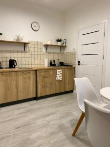 a kitchen with wooden cabinets and a clock on the wall at AT Apartament in Pasłęk +8 photos
