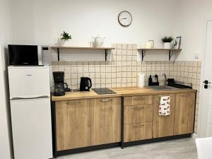 a kitchen with a white refrigerator and wooden cabinets at AT Apartament in Pasłęk