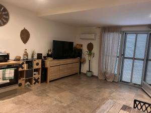 a living room with a flat screen tv on a wooden cabinet at F3 CENTRE de ST-FLORENT in Saint-Florent