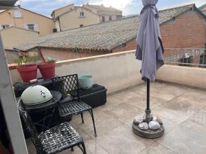 an umbrella on a balcony with a table and chairs at F3 CENTRE de ST-FLORENT in Saint-Florent