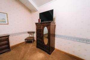 a room with a television on a dresser with a mirror at Riverside Motor Lodge - Pigeon Forge in Pigeon Forge