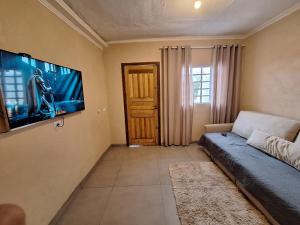 a living room with a couch and a flat screen tv at Ampla, com 5 vagas de carro e bem próxima das empresas da região in São José dos Pinhais