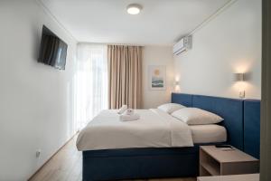 a bedroom with a blue and white bed and a television at Alemaris Resort in Baška Voda