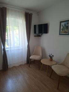 a living room with two chairs and a tv and a window at Malin Guesthouse in Skradin