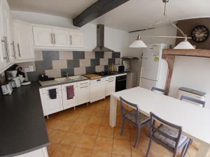 a kitchen with white cabinets and a table and chairs at Le gîte "Et puits c'est tout!" in Préty