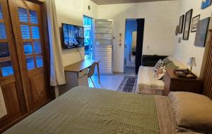 a bedroom with a bed and a desk and a television at Estúdio aconchegante com cozinha externa e quintal in Morro do Chapéu