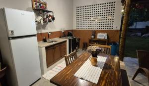 a kitchen with a wooden table and a refrigerator at Estúdio aconchegante com cozinha externa e quintal in Morro do Chapéu +1 photo