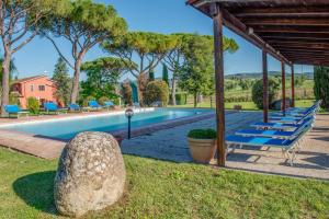 a pool with blue lounge chairs and a pavilion at Capracotta in Montemassi