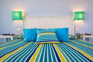 a bedroom with a bed with blue and yellow stripes at Hotel O'scià in Lampedusa