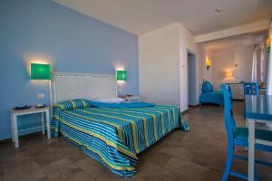a bedroom with a bed and a table and chairs at Hotel O'scià in Lampedusa