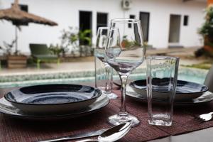 a table with two wine glasses and plates on it at Résidences AMAN in Morofé
