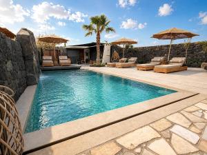 a swimming pool with chairs and umbrellas in a backyard at Santa Mar ECO Suites in Karterados