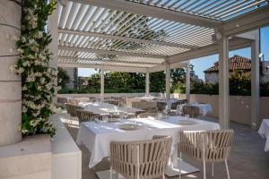 a restaurant with white tables and chairs under a pergola at Heritage Hotel Lucia in Dubrovnik
