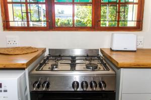 a stove top oven in a kitchen with windows at Cote Cottage in Somerset West