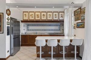 a kitchen with a counter and white stools at Casa Donata by Gottschalk in Lierna