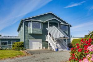 a green house with a garage and flowers at Charming Sequim House w/ Olympic Peninsula Views! in Sequim