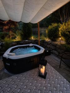 a jacuzzi tub under an umbrella with a candle at Wellspace Forest Retreat in Karlovy Vary
