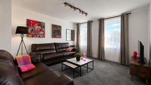 a living room with a leather couch and a table at GALLOWGATE - CITY CENTRE - Free PRIVATE PARKING in Aberdeen