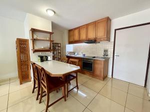 a kitchen with wooden cabinets and a table with chairs at TAHITI - Condo Ariitea in Pirae +4 photos