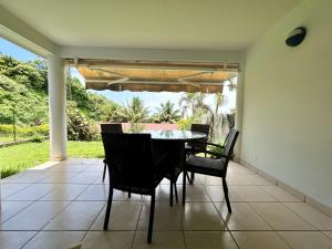 a dining room with a table and chairs on a patio at TAHITI - Condo Ariitea in Pirae