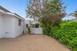 a white house with a tree and a driveway at Cote Cottage in Somerset West