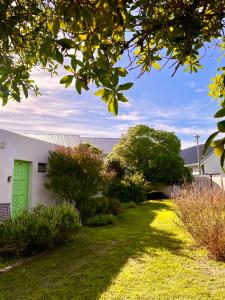 a house with a green door in a yard at Kelp Cottage - Two Private Garden en-suite Rooms in Gansbaai