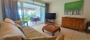 a living room with a couch and a tv and a table at TAHITI - Condo Ariitea in Pirae