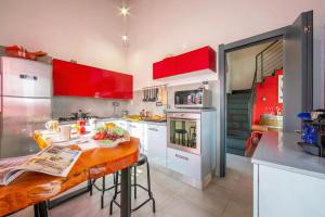 a kitchen with red cabinets and a wooden table at Villa Laura Private Pool and Garden near Lake Maggiore for 9 - Happy Rentals in Besozzo