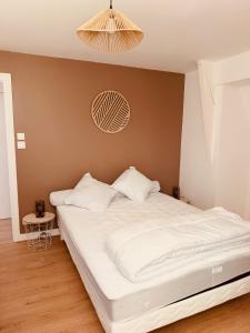 a bedroom with a bed with white sheets and a chandelier at Gîte La Chaumière avec Piscine in Nailhac +5 photos