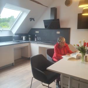 a woman sitting at a table reading a book at Ferienwohnung Vital am Bach "Dhron" in Neumagen-Dhron