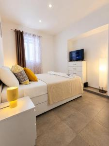 a white bedroom with a bed and a tv at Komiža Sea Breeze in Komiža