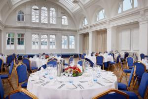 una stanza con tavoli bianchi e sedie blu di Titanic Hotel Belfast a Belfast