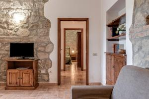 a living room with a tv and a stone wall at Capracotta in Montemassi