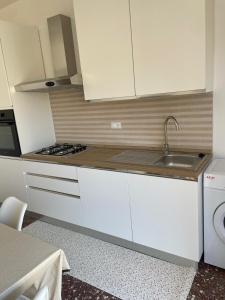 a kitchen with white cabinets and a sink at Gemma's Apartments in Mazzeo