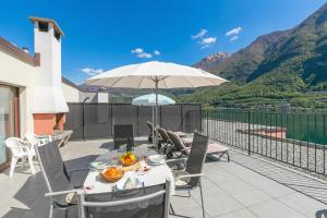 a patio with a table and an umbrella at Casa Bader - Lake View Apt with Pool & Sauna - Happy Rentals in Riva San Vitale