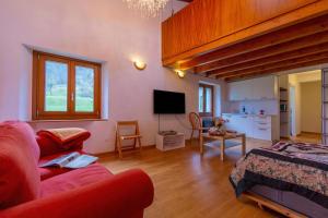 a living room with a red couch and a tv at Casa Gialla Lake Lugano Townhouse for 5 - Happy Rentals in Pugerna