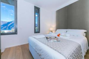 a white bedroom with a large bed with a window at Casa Basilico with Lake View and Private Garage - Happy Rentals in Lugano