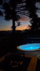 a jacuzzi tub with a sunset in the background at Chalé Refúgio do Lobo in São Bento do Sapucaí
