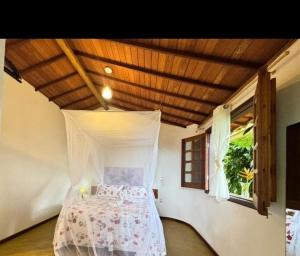 a bedroom with a bed with a canopy and a window at Pousada Aldeia in Ilha de Boipeba