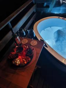 a table with glasses and plates of food next to a bath tub at Chalé Refúgio do Lobo in São Bento do Sapucaí