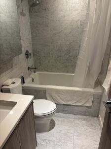 a bathroom with a toilet and a tub and a sink at Brentwood Retreat in Burnaby