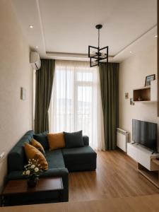 a living room with a green couch and a television at Vazi Aparthotel in Tbilisi City