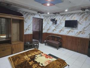 a bedroom with a bed and a tv on a wall at Mughal E Azam Hotel in Murree