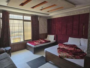 two beds in a room with red walls and windows at Mughal E Azam Hotel in Murree