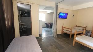 a room with two beds and a tv on the wall at Pousada Cantinho e Sossego casa 5 in Vespasiano