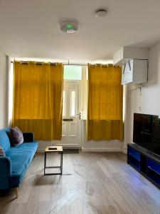 a living room with yellow curtains and a blue couch at Accessible Town Centre 1 bed Flat Kettering Wi-FI in Kettering