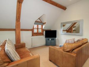a living room with two leather couches and a flat screen tv at Pultheley Cottage in Montgomery