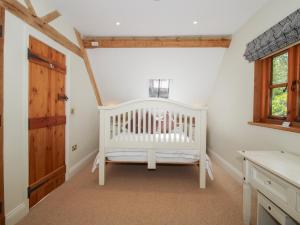 a white crib in a room with a window at Pultheley Cottage in Montgomery