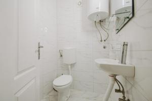a white bathroom with a toilet and a sink at Kuća Mitića in Pirot +20 photos